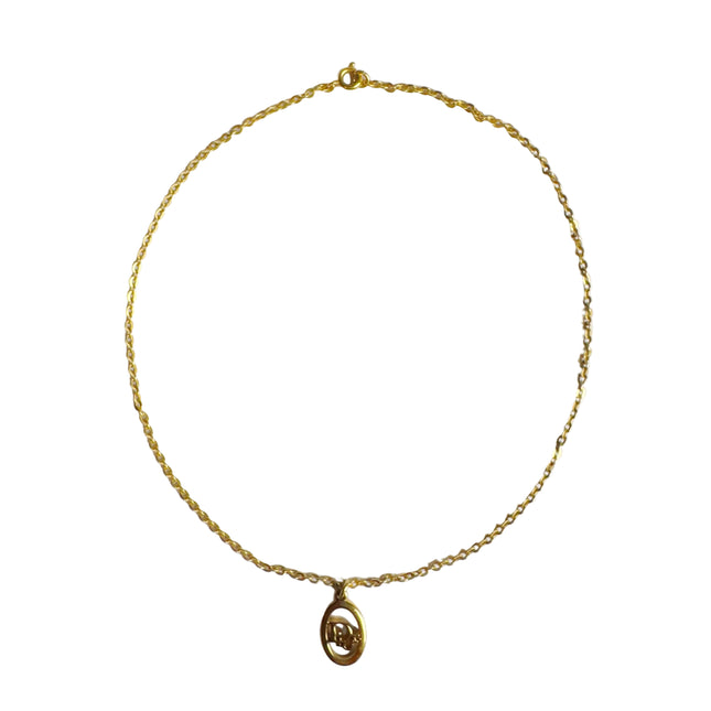 Christian Dior gold metal logo pendant necklace with "Dior" letters sitting inside oval